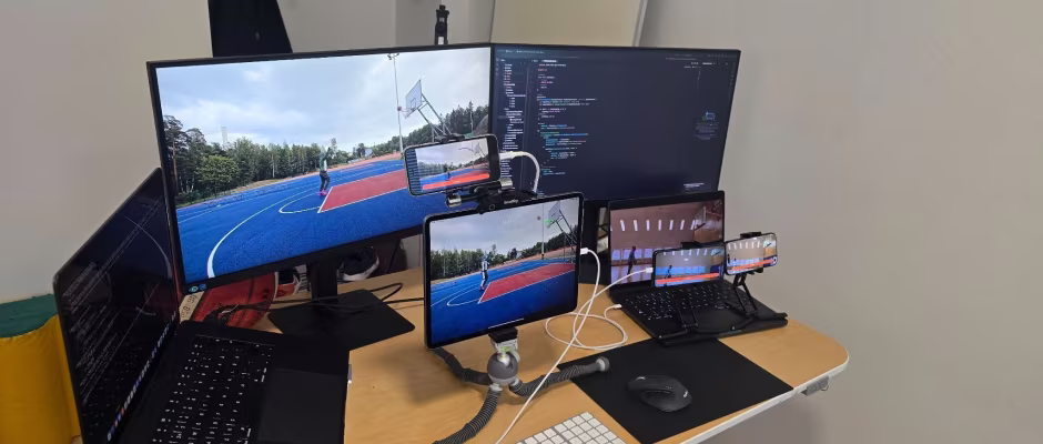 A desk setup with multiple screens and devices displaying a basketball game